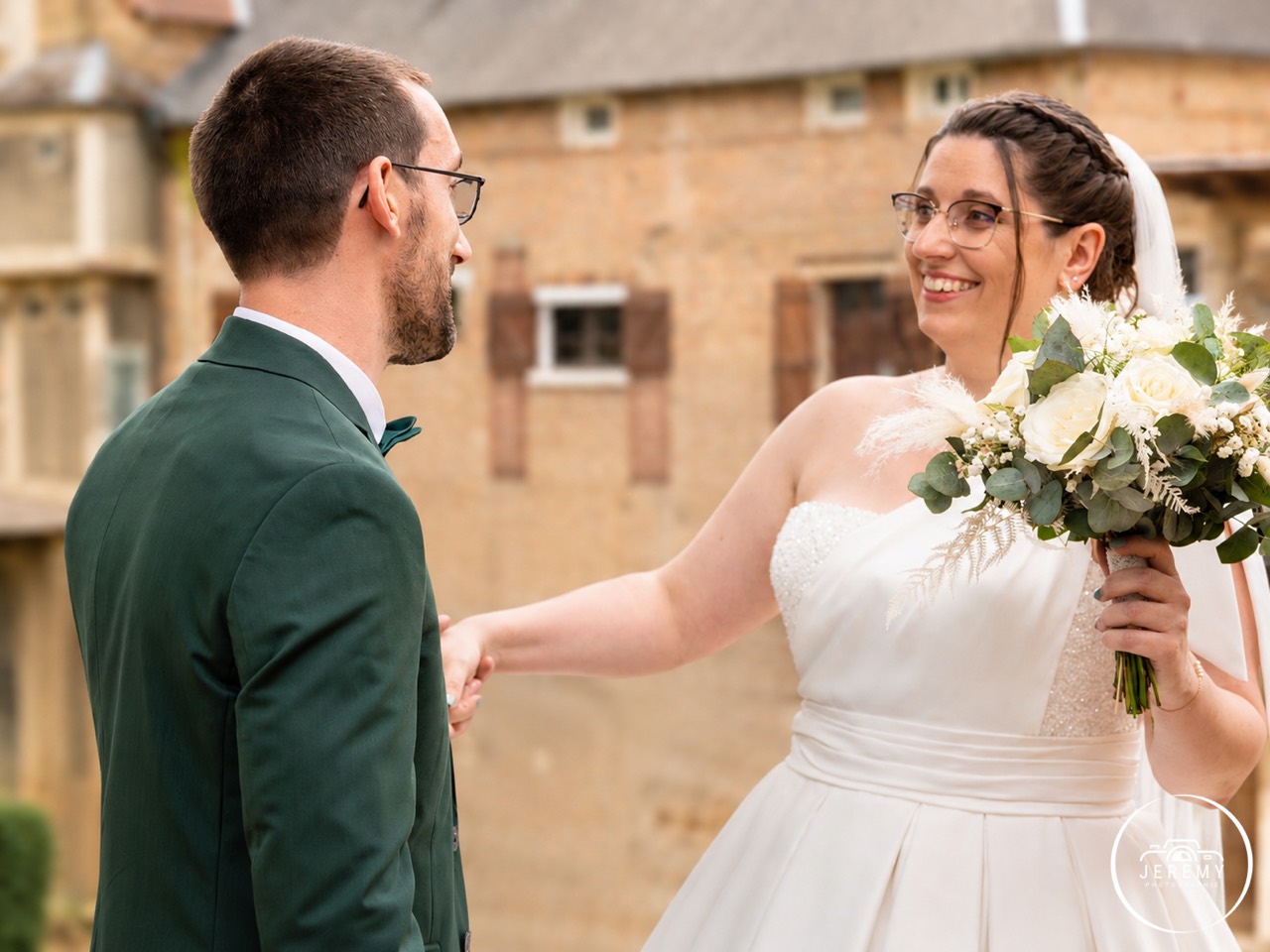 Mariée souriante avec bouquet devant le marié